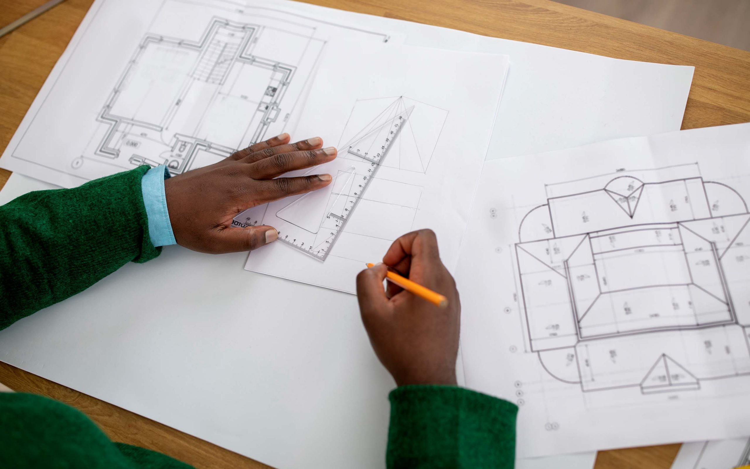 Close shot of plans, tools, and hands reviewing drawings.